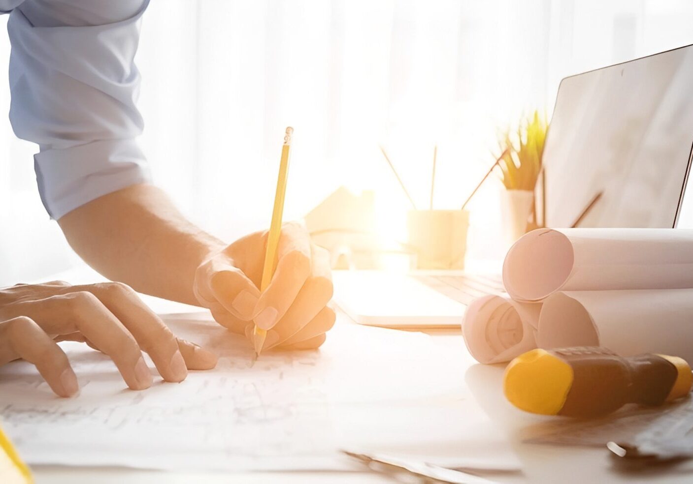 Architect drawing plans at a sunlit desk.